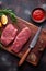 Raw beef steak with vegetables. Horizontal view of red meat on wooden cutting board.