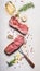 Raw beef Striploin steaks with oil , spices and meat fork on white stone background, top view, flat lay