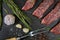 Raw beefsteak with seasonings, black background, top view
