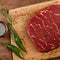 raw black meat steak with spices and rosemary. black background with top view