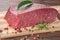 Raw boneless beef meat cut with seasoning on wooden table, close