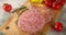 Raw burger meat on a wooden cutting board.