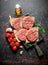 Raw burgers with tomatoes, rosemary and oil