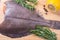 Raw butchered flounder on a cutting board with herbs and spices.