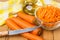 Raw carrot in bowl, bottle vegetable oil, knife and napkin