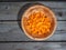 Raw carrot, diced in a deep plate. Shot from above on a wooden old table. Close-up