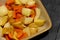 Raw carrot, onion and potato in a ceramic dish prepared for roasting