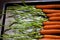 Raw Carrots on Metal Cookie Sheet in a row with Stems Attached