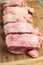 Raw chicken backs lined up on a wooden board in a kitchen top view