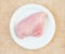 Raw chicken breast fillets on a white plate top view