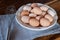 Raw chicken eggs on white plate with whisk on wooden background. Ready to start the cooking concept