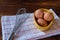 Raw chicken eggs on yellow bowl with whisk on wooden background. Ready to start the cooking concept