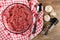 Raw chicken forcemeat in transparent bowl, spoon on napkin, garlic, condiment in jar on wooden table. Top view