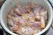 Raw chicken legs in a bowl in a marinade of olive oil, various seasonings and chopped lemon. Preparation of diet chicken