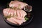 Raw chicken meat slices on black background. Culinary gastronomy cooking background.Thinly sliced chicken fillet with rosemary.