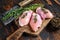 Raw Chicken skinless thigh fillet on a wooden cutting board. Black background. Top view