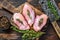 Raw Chicken skinless thigh fillet on a wooden cutting board. Black background. Top view