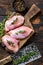 Raw Chicken skinless thigh fillet on a wooden cutting board. Black background. Top view