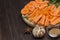 Raw chopped carrots on cutting board. Garlic and mustard seeds on table