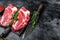 Raw chuck eye roll steaks premium beef meat on a cutting board. Black background. Top view. Copy space