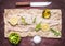 Raw cod with lemon and herbs, salt and butter and a knife on paper on wooden rustic background top view close up