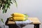 Raw corn cobs with leaves on a wooden table over grey wall background. Fresh corncobs on light brown wooden table, rustic style.