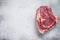 Raw cowboy steak or rib eye on the bone. Marble beef. Gray background. Top view. Copy space