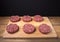 Raw cutlet of minced meat on a wooden cutting board on black background. Toned