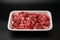 Raw diced meat chopped in cubes in a white styrofoam container isolated on black background copy space