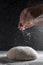 Raw dough and sprinklling flour over dark background. Cooking bread or pizza. Action, movement food photo