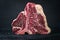 Raw dry aged wagyu porterhouse beef steak with large fillet piece on a black burnt wooden board