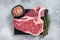 Raw dry aged wagyu porterhouse beef steak, uncooked T-bone on marble board with thyme. Gray background. Top view