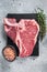 Raw dry aged wagyu porterhouse beef steak, uncooked T-bone on marble board with thyme. Gray background. Top view