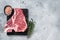 Raw dry aged wagyu porterhouse beef steak, uncooked T-bone on marble board with thyme. Gray background. Top view. Copy