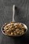 Raw, dry, uncooked brown lentil legumes in metal scoop on wood table background with selective focus