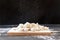 raw dumplings on a cutting Board on a dark background, flour pours on the dumplings on top