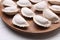 Raw dumplings (varenyky) on wooden plate, closeup