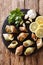 raw edible sea snails, whelks close-up and lemon, parsley, garlic on a slate board.Vertical top view from above