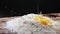 Raw egg and broken shell fall down into flour pile on table