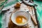 Raw egg broken into a white bowl with yolk and protein, next to the shell, fork and towel on a rusty metal background