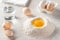 Raw egg in a heap of whole grain flour, a glass of water, eggs and eggshells on the kitchen table.