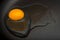 Raw egg on non-stick frying pan close-up. Kitchen. Black background. Cooking food concept. Yolk and protein of egg.