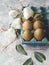 Raw eggs in a carton for eggs with white flowers on a marble white table, ready for painting Easter, selective focus