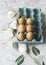 Raw eggs in a carton for eggs with white flowers on a marble white table, ready for painting Easter, selective focus