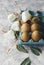 Raw eggs in a carton for eggs with white flowers on a marble white table, ready for painting Easter, selective focus