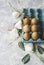 Raw eggs in a carton for eggs with white flowers on a marble white table, ready for painting Easter, selective focus