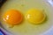 Raw eggs with colorful yolks in a plate.