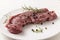 Raw entrecote steak with rosemary and spices on a white plate