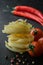 Raw fettuccine pasta with fresh tomato, black peppercorns and chili peppers