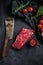 Raw, flap or flank, also known Bavette steak near butcher knife with pink pepper and rosemary. Black background. Top view vertical
